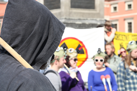Energetyce jądrowej w zasadzie od samego początku towarzyszyły protesty Zdjęcie przedstawia grupę młodych kobiet i mężczyn. Część z nich ma nałożone na głowy maski ochronne. W tle widoczny jest biały transparent, na którym umieszczono przekreślony symbol radioaktywności