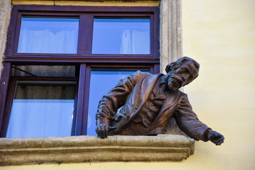 The photo shows the statue of Ignacy Łukasiewicz in Lviv, who gazes out of a window of a tenement, looking at the statue of his colleague Jan Zeh.