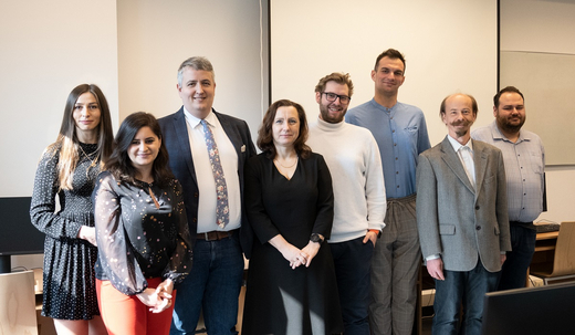 The photo shows the team of the laboratory who are standing next to one another in a line, smiling.