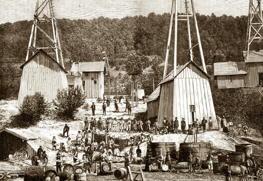 The picture shows a historical photograph of the first oil wells in Galicia. It presents tall towers, working men, and entrepreneurs.