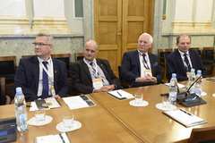 Zdjęcie wykonane w Auli AGH. Przy stole siedzi czterech Prorektorów AGH. Ubrani są w garnitury. Na blacie stołu, podobnie jak na pozostałych zdjęciach: plastikowe butelki z wodą, szklanki, kartki, mikrofony.