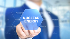 Na pierwszym planie grafiki znajduje się napis "nuclear energy" w kolorze białym umieszczony na niebieskim tle. Napis wpisany jest sześciokąt. Na drugim planie, w lustrzanym odbiciu, na sześciokąt wskazuje palcem mężczyzna w garniturze i krawacie w kolorze granatowym oraz koszuli w kolorze białym.