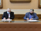 Przedstawiciele AGH oraz IMP podpisują porozumienie, siedząc przy stole.
