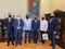 Na zdjęciu sześciu mężczyzn. Stoją obok siebie w rzędzie. Ich twarze i nosy zasłaniają maseczki. Na ścianie za mężczyznami, ponad ich głowami, wisi portret Stanisława Staszica. Zdjęcie zrobione w gabinecie Rektora AGH.